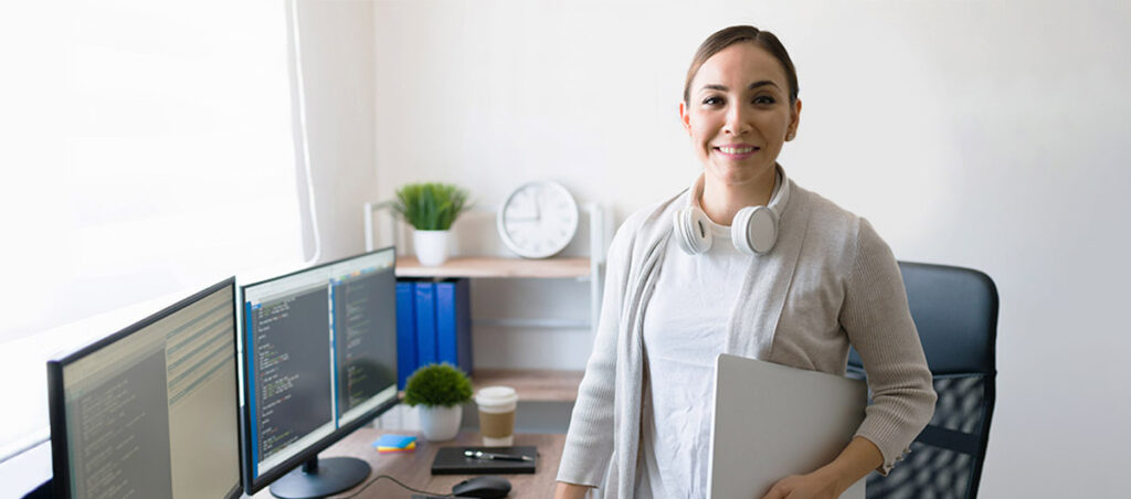 Eine Frau mit Laptop unter ihrem Arm sicherst sich das nötige Praxiswissen – und ist mit dem anerkannten IHK-Berufsabschluss bestens gerüstet für einen Neustart in der kaufmännischen IT-Berufswelt.