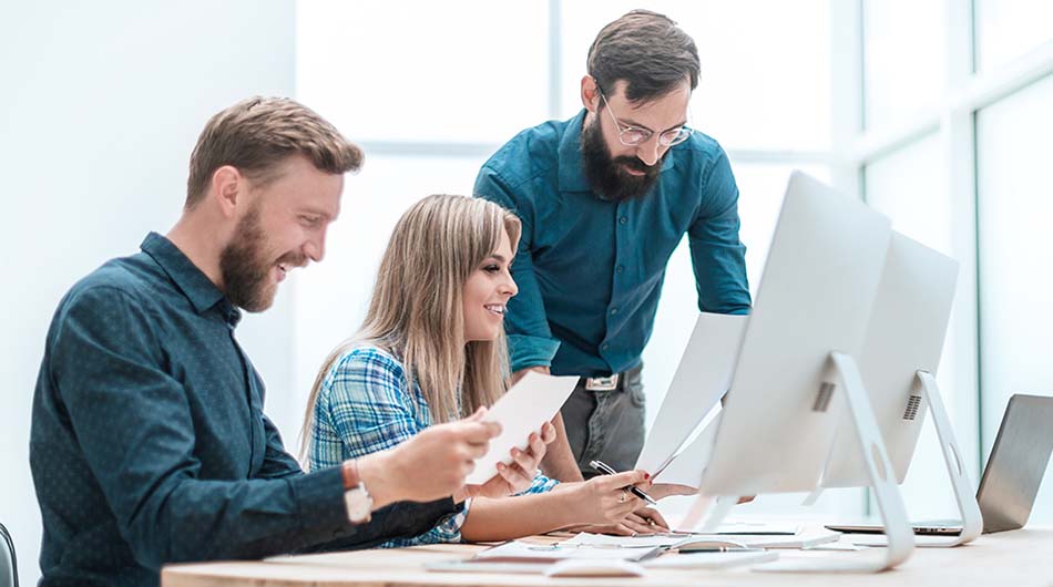 Drei Personen arbeiten gemeinsam an Computern im Schulungsraum.